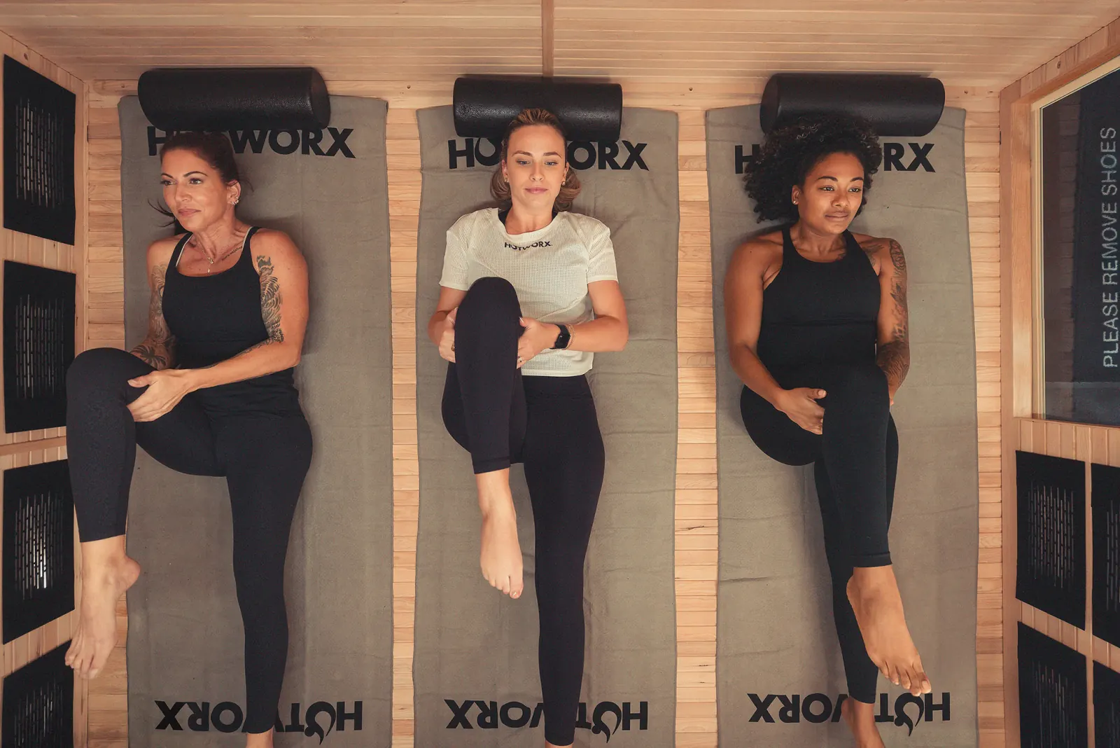 Three women exercising on mats in a HotWorx sauna