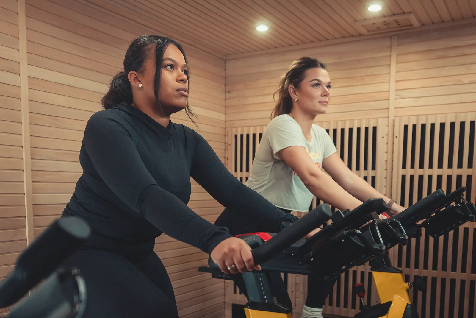 Two women cycling in an infrared sauna studio