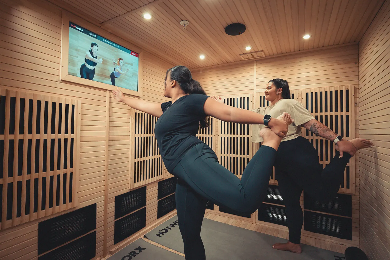 Two women doing yoga in a HotWorx sauna