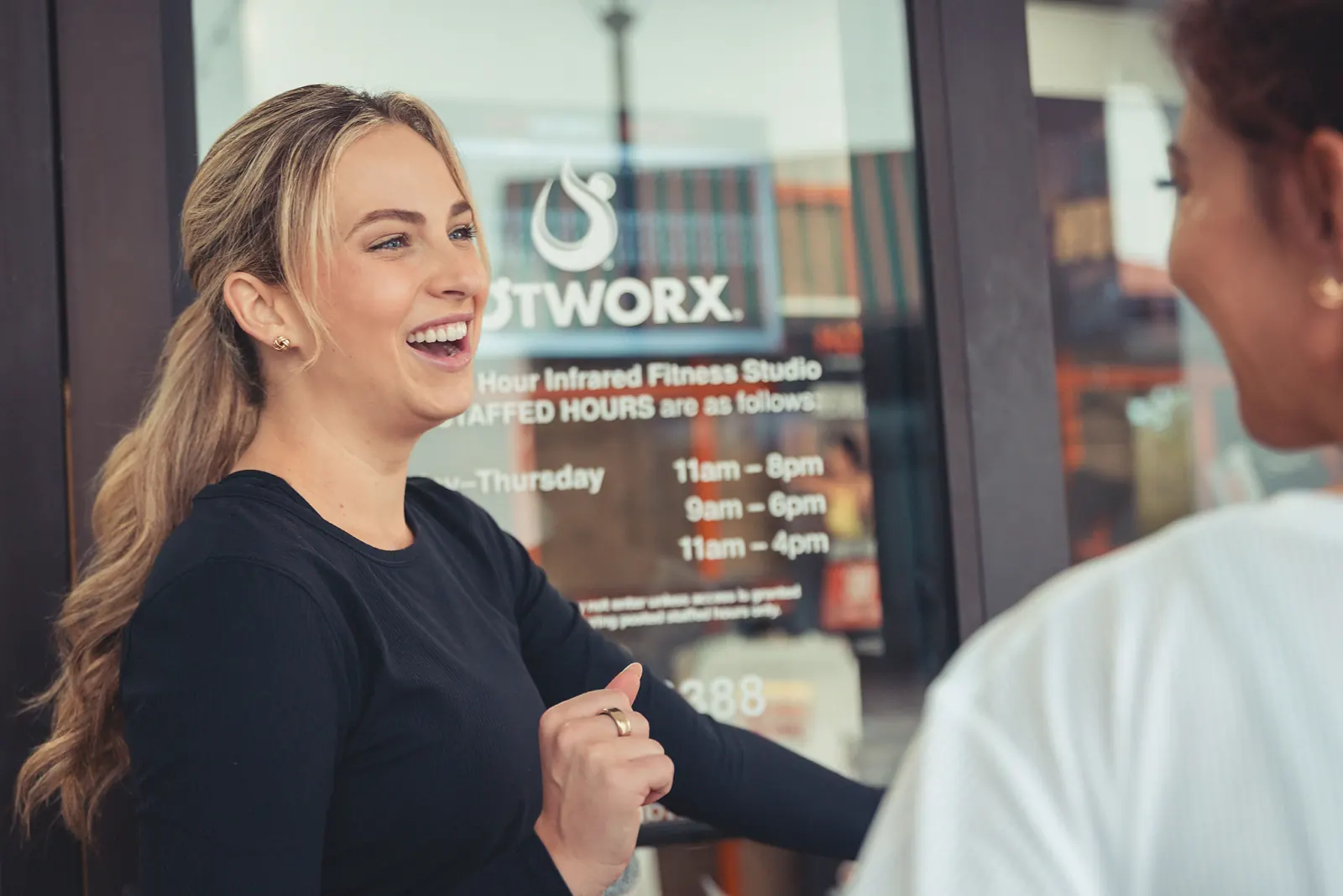 Woman laughing in front of HotWorx infrared fitness studio